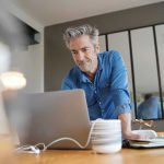 Mature business man working from contemporary home looking on his computer for a work from home policy