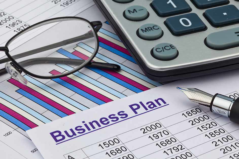 Business plan image with a calculator, glasses, pen and paper with facts and figures on it