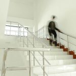 A person walking down a flight of stairs in an apartment complex showing a potential for a slip and fall accident.