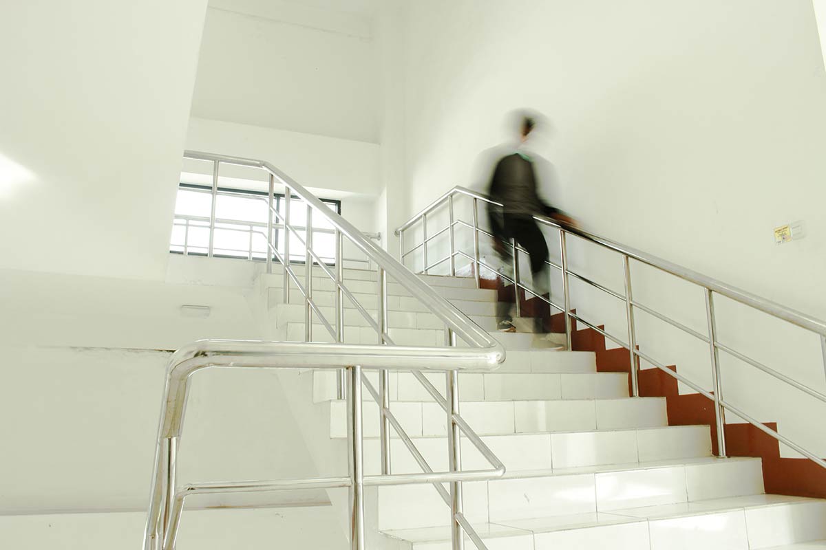 A person walking down a flight of stairs in an apartment complex showing a potential for a slip and fall accident.