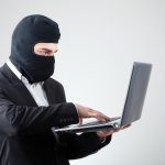 Picture of an employee in a business suit accessing a stolen customer list on his personal laptop.