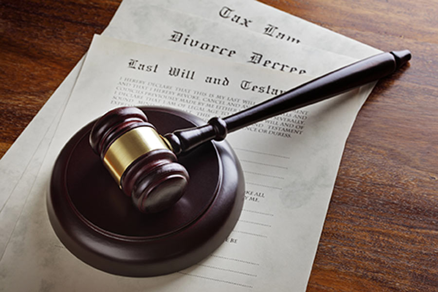 A gavel and legal documents signifying will and trust planning on a wooden surface.