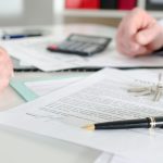 A real estate attorney reviewing closing documents with a couple in a modern office