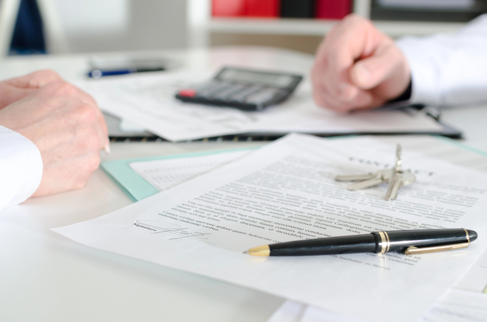 A real estate attorney reviewing closing documents with a couple in a modern office